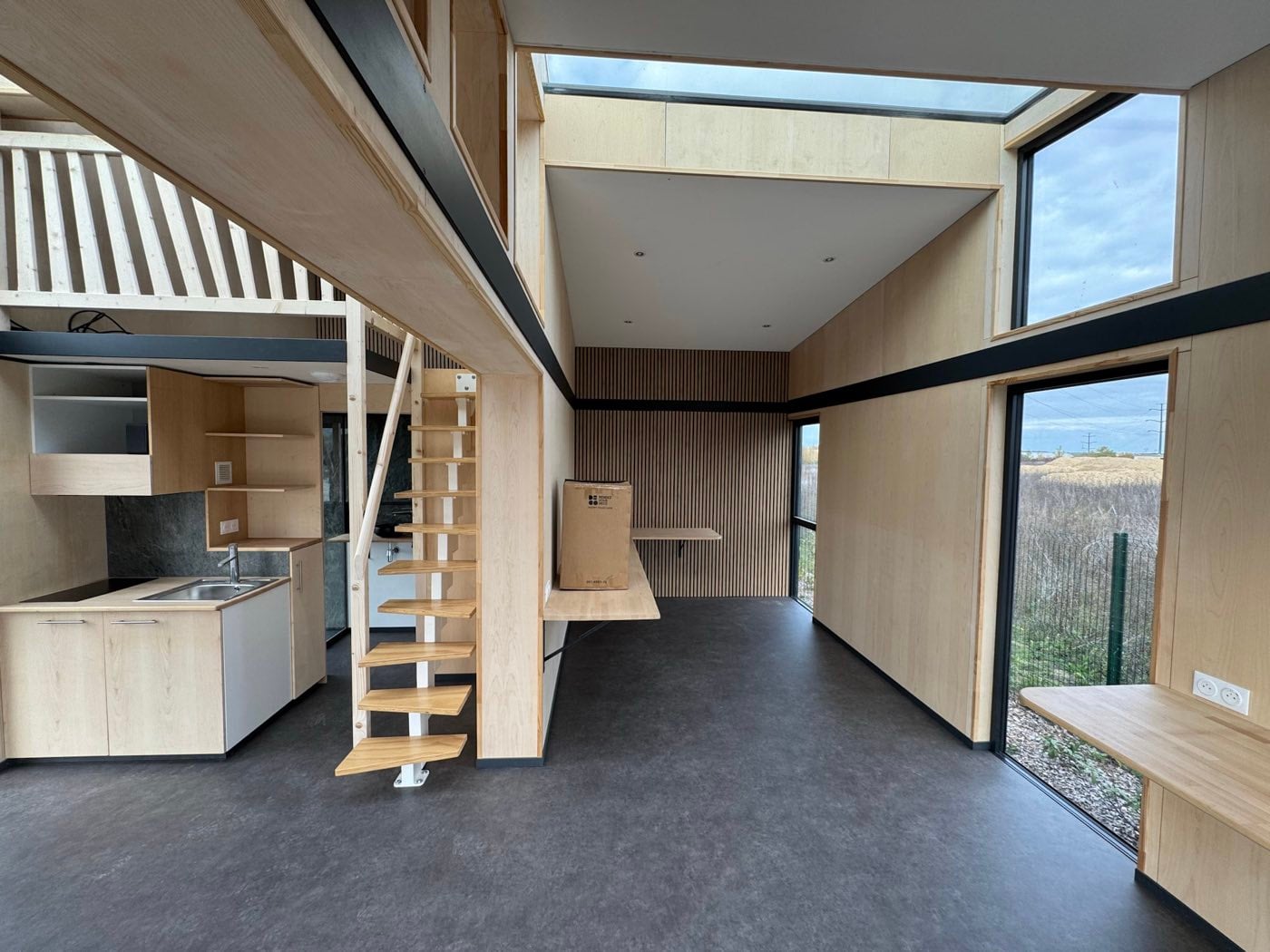 Intérieur d'un module avant emménagement : cuisine, escalier vers la mezzanine et verrière filante