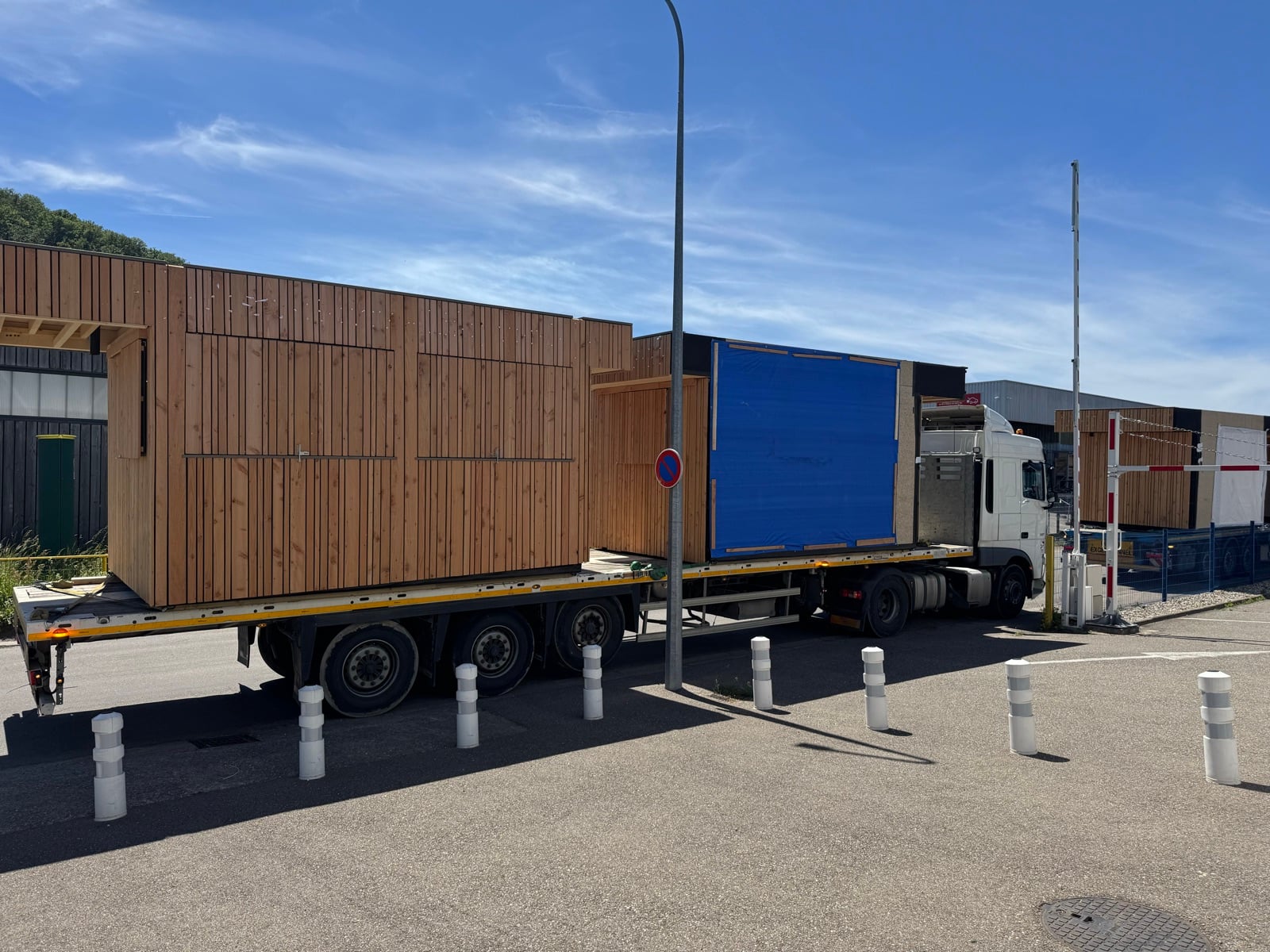 Un module en bardage mélèze sanglé sur sa remorque, sur le parking de l'atelier